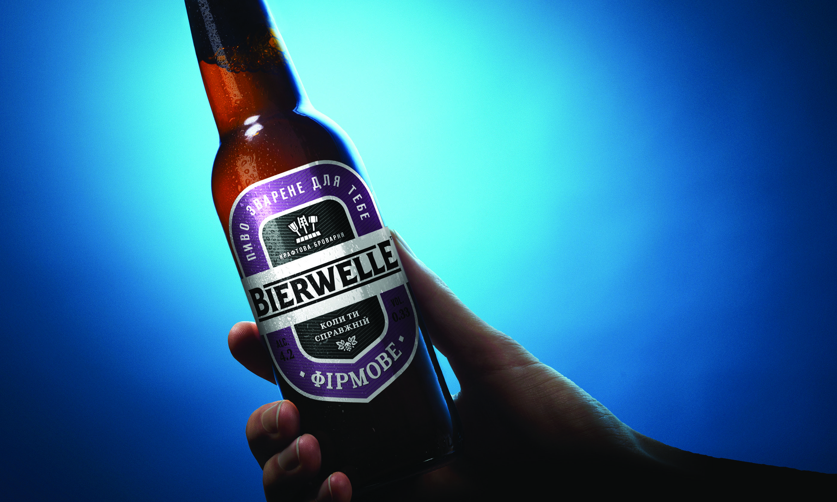 Етикетка Bierwelle «Фірмове» — пляшка в руці на блакитному фоні